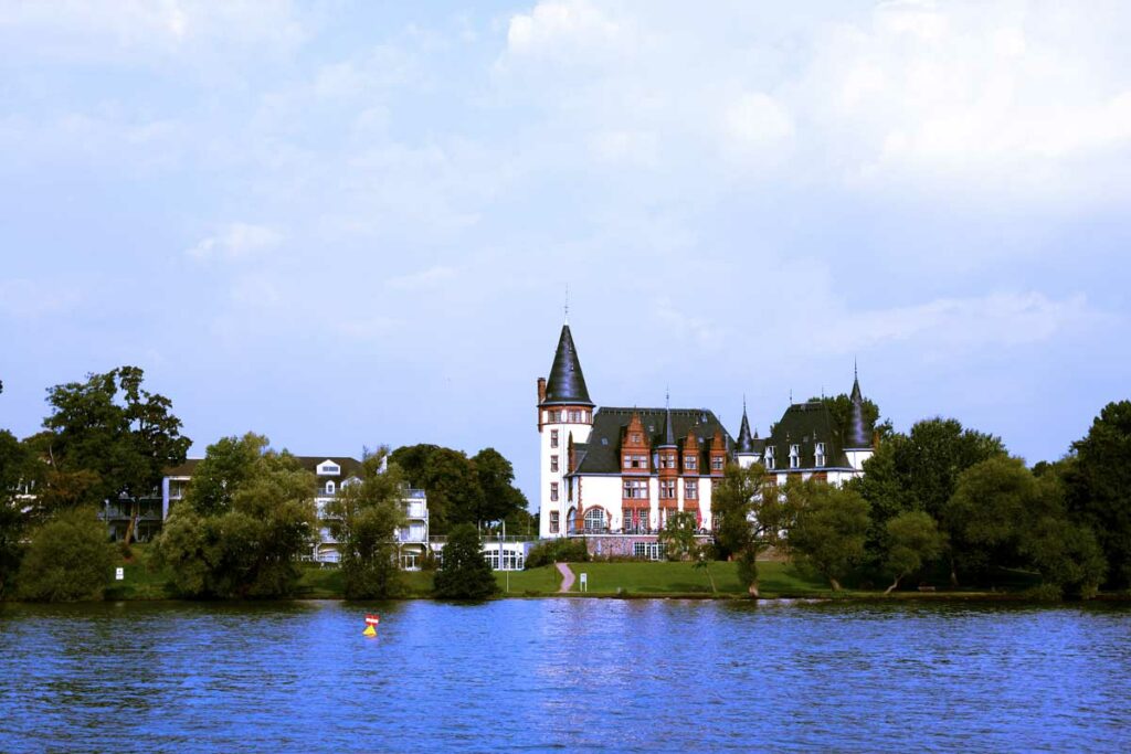 Blick von Bord eines Hausbootes auf das als Hotel genutzte Schloss Klink am Ufer der Müritz